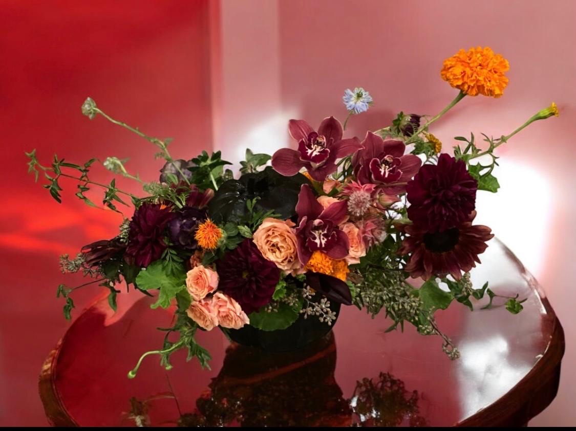 A vivid sculptural floral arrangement set against a saturated colored wall at a brand activation